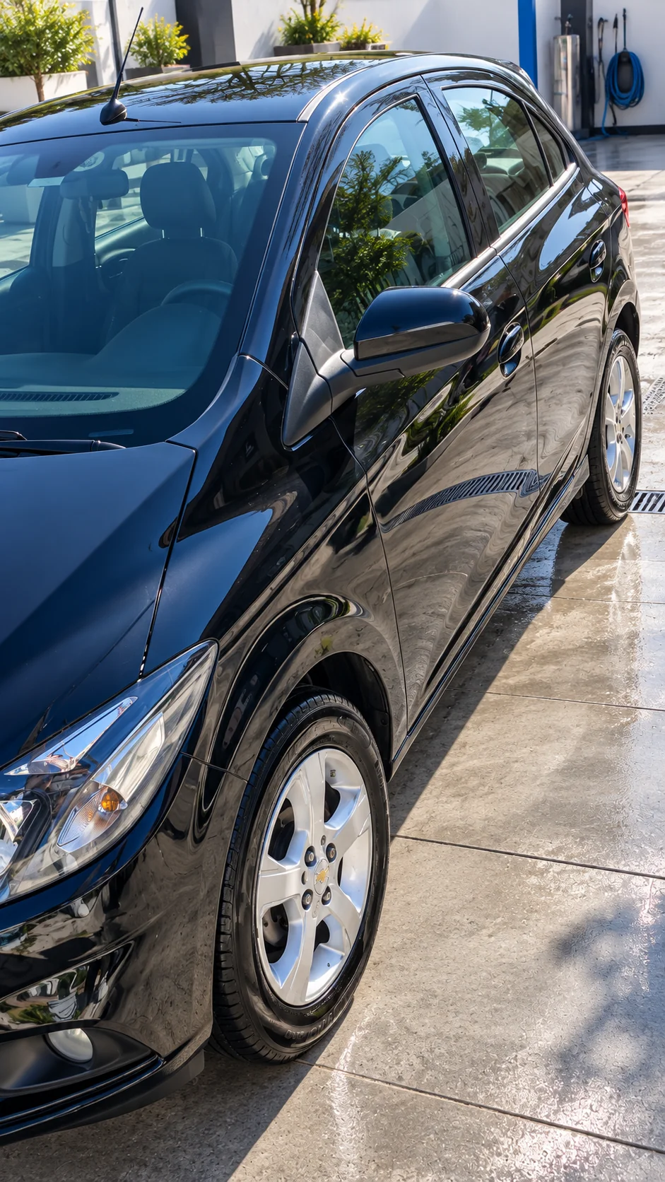 Chevrolet Onix negro, detalle lateral y pintura, en un lavadero con ambientación recreada.