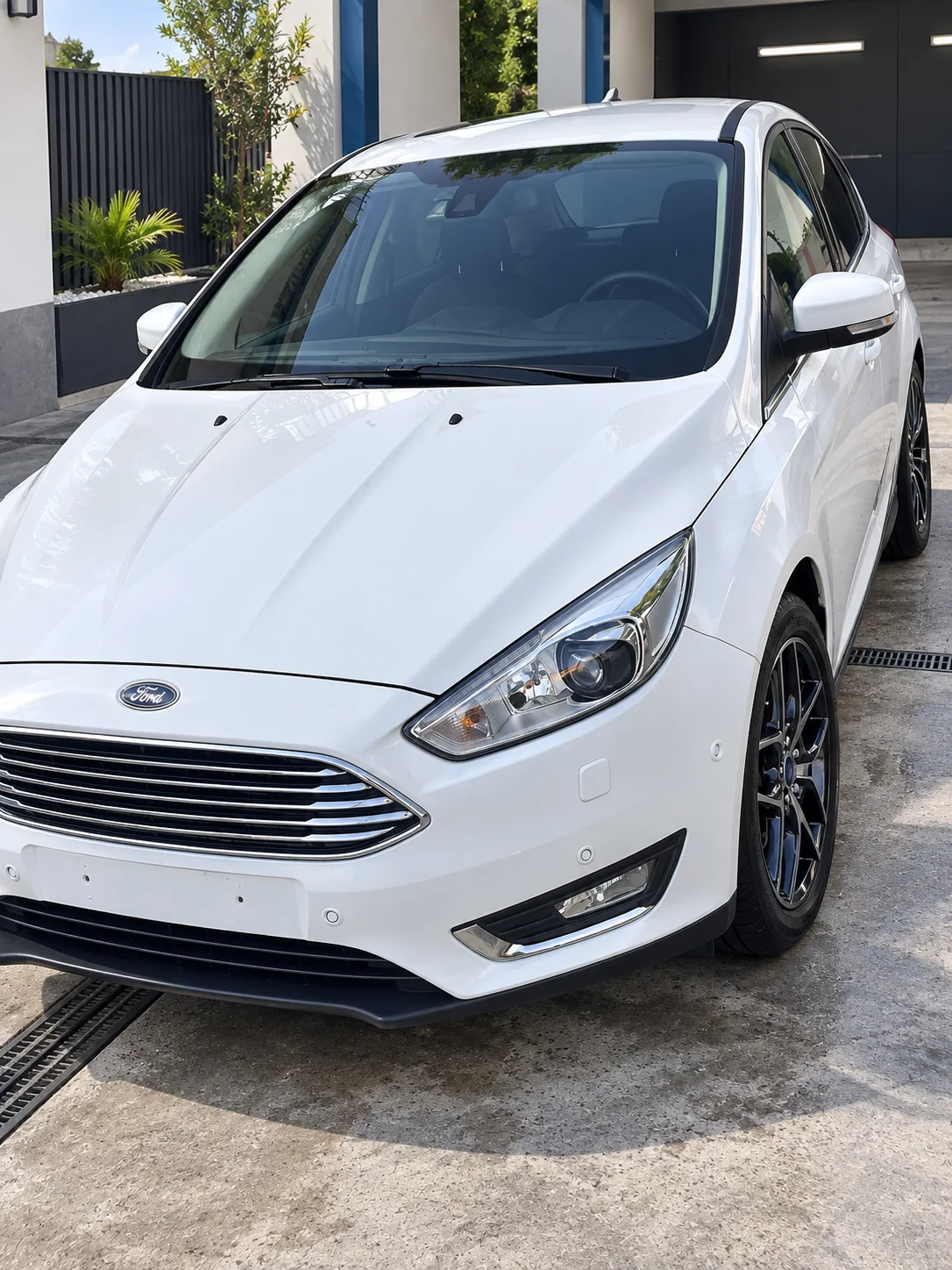 Ford Focus III blanco, vista delantera, en un lavadero con ambientación recreada.